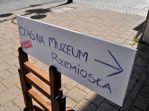Drogowskaz kierujący zwiedzających do muzeum z napisem: czas na muzeum rzemiosła