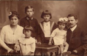 Fotografia w kolorzer sepii. Po lewej stronie Mężczyzna, po lewej kobieta, między nimi czworo dzieci
