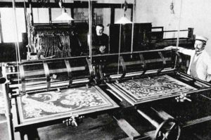 Fotografia czarno-biała: dwóch mężczyzn przy maszynach do tkania