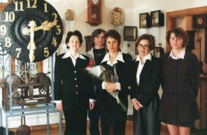 Pięć osób: 4 kobiety i mężczyzna odświętnie ubrani stoją przy tarczy zegara