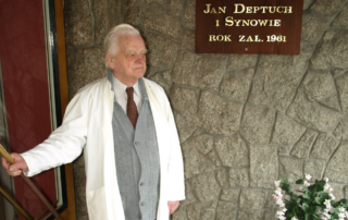 Mężczyzna stoi przy tablicy: Firma Jan Deptuch i Synowie