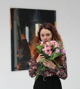 Artystka z bukietem kwiatów przy obrazie
